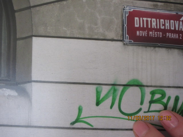 main posée sur la photo d'un graffiti rouge à prague